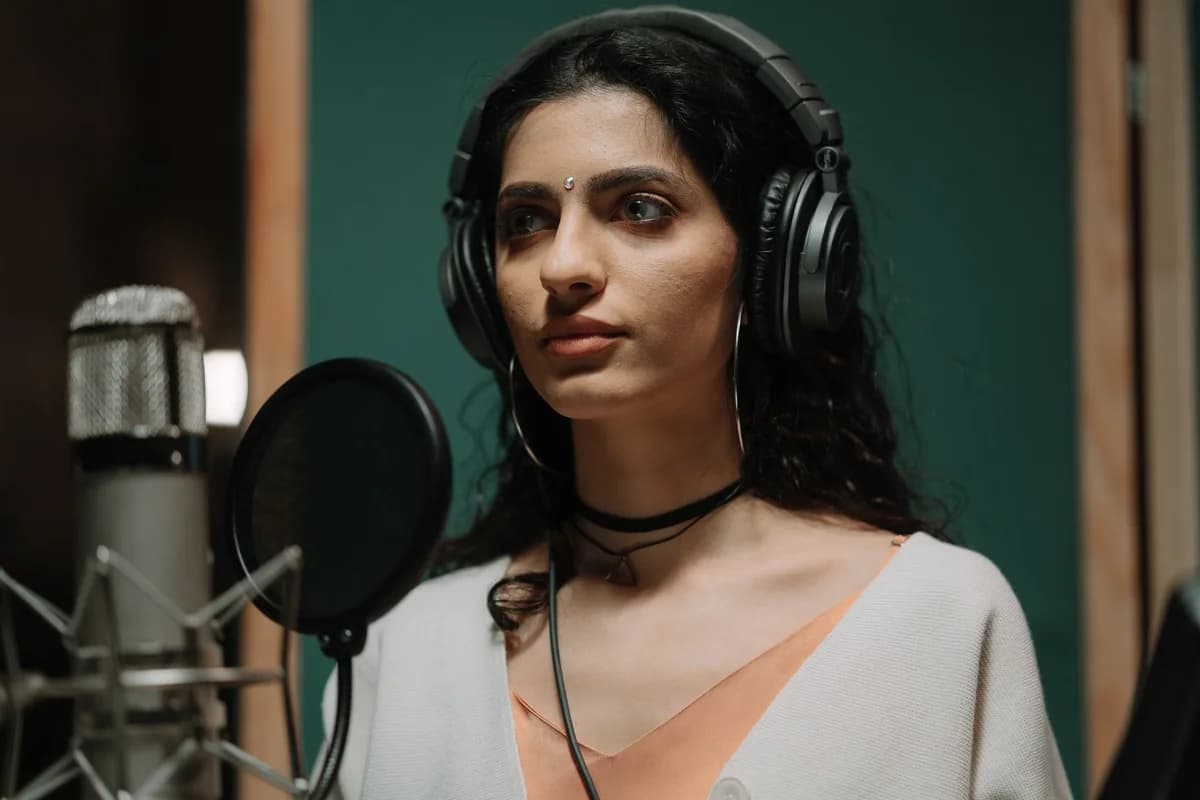 Woman wearing headphones recording vocals in a music studio