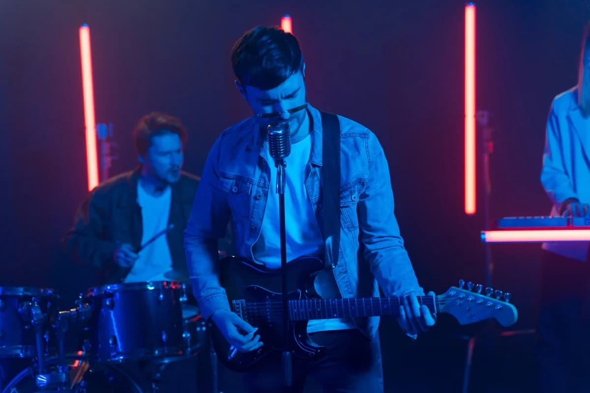 A rock band performs on stage under blue and red neon lights.
