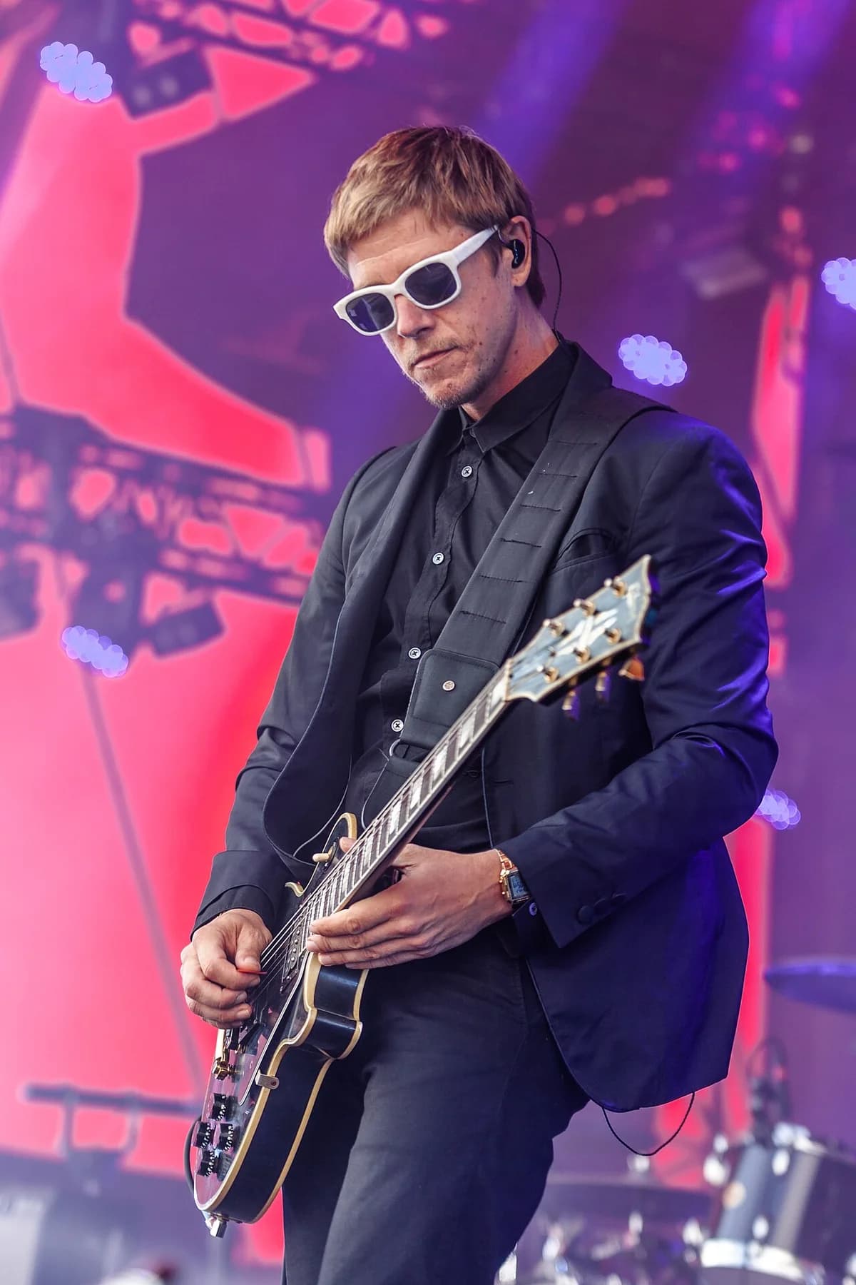 Paul Banks performs on stage with a guitar at Roskilde Festival.