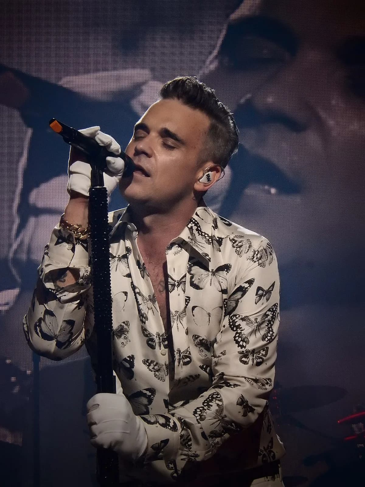 Male singer performing live with a microphone and butterfly shirt