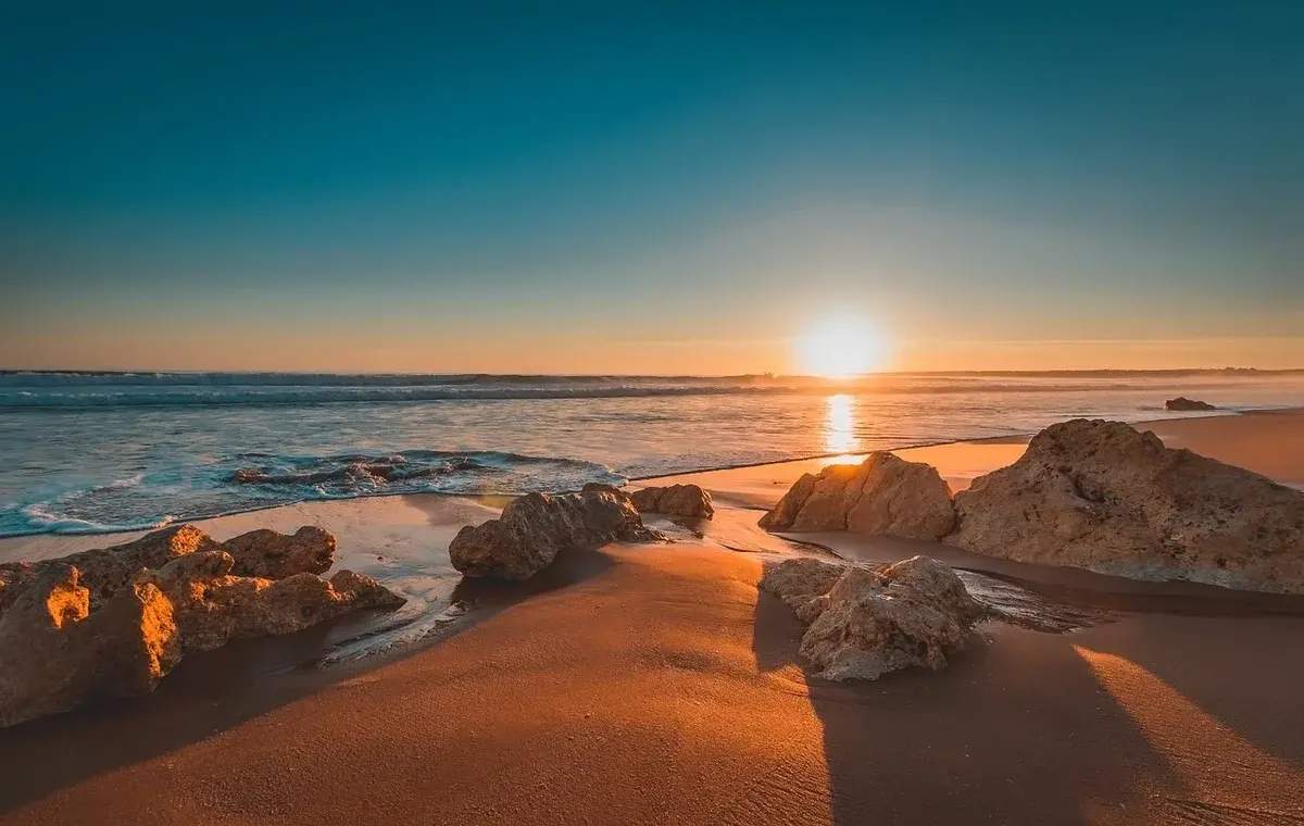 Sunset over a rocky beach and calm sea in Portugal.
