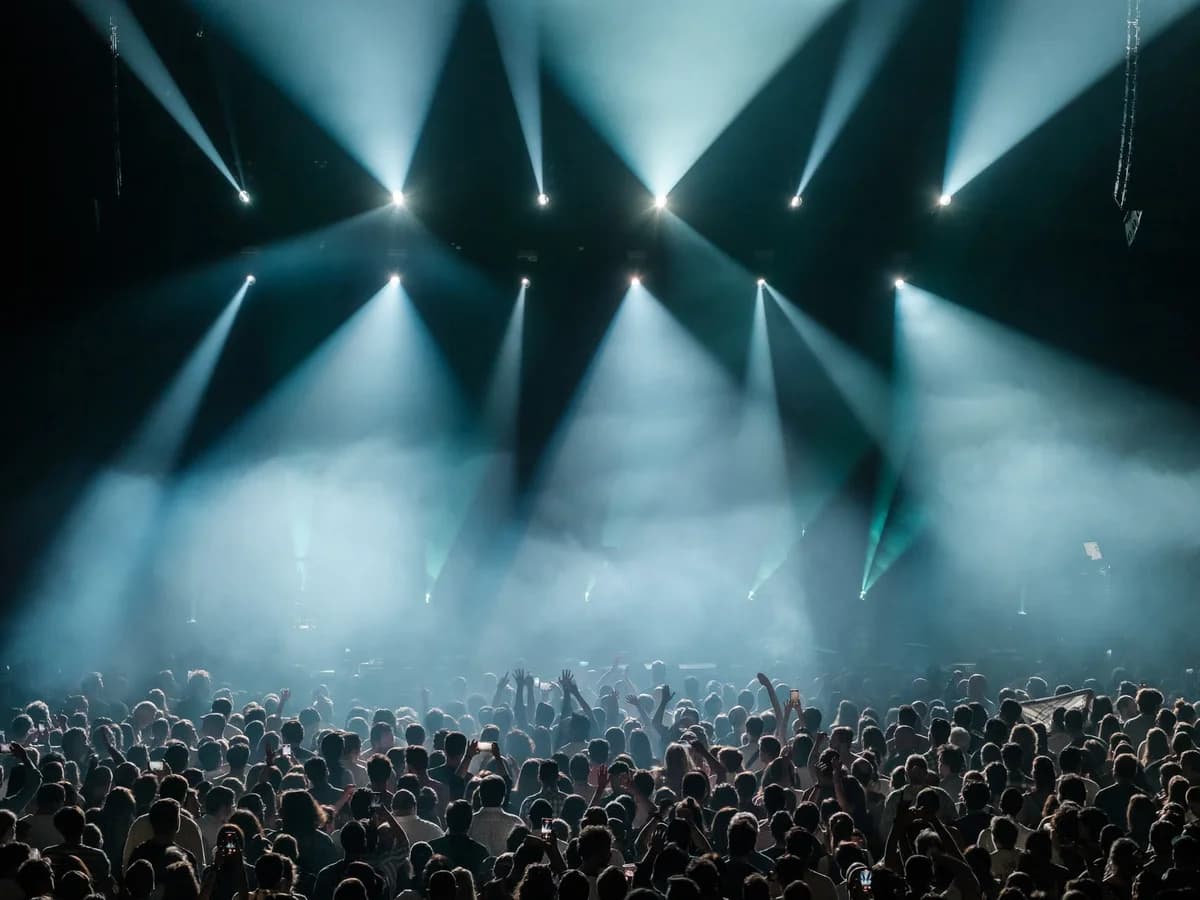Concert crowd under bright white stage lights with fog