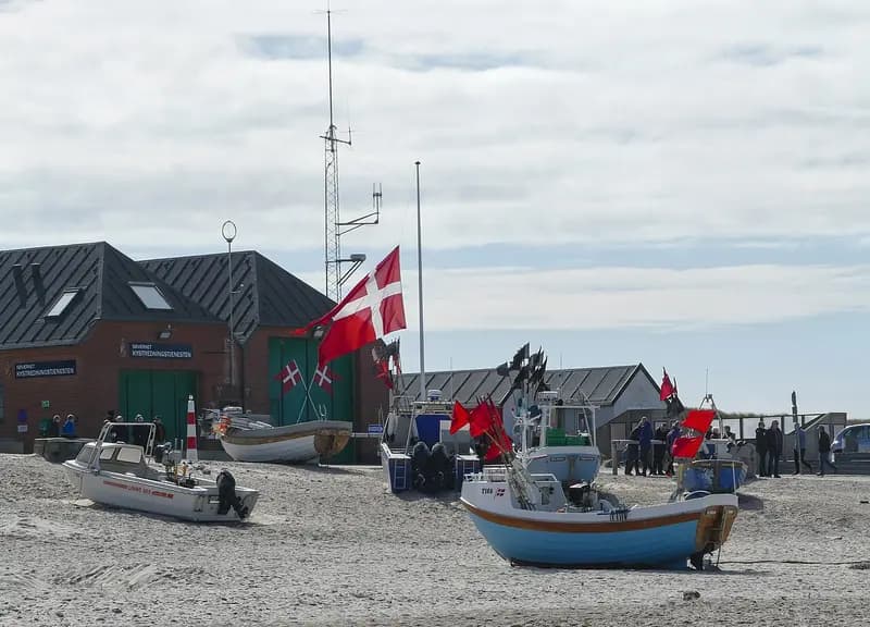 Danish flag flying at Nørre Vorupør beach with fishing boats nearby