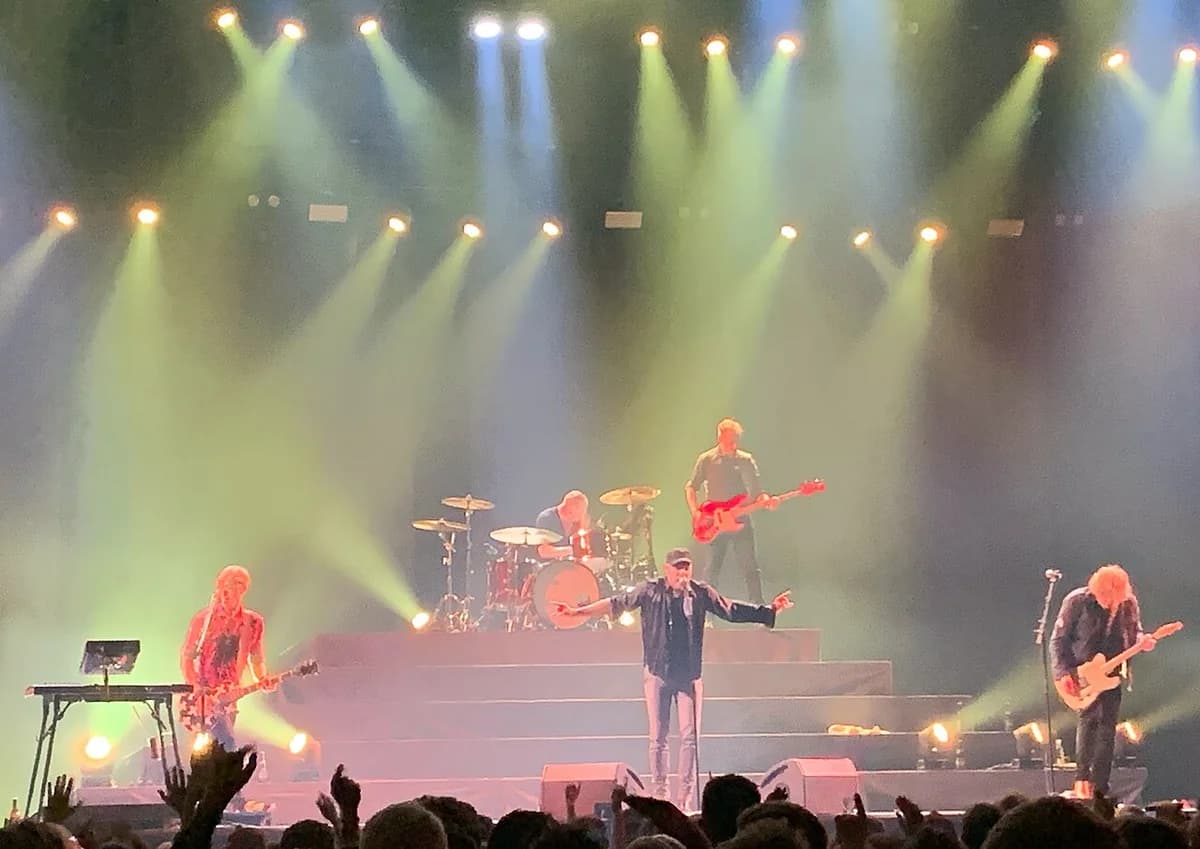 A rock band performing on stage under bright lights.