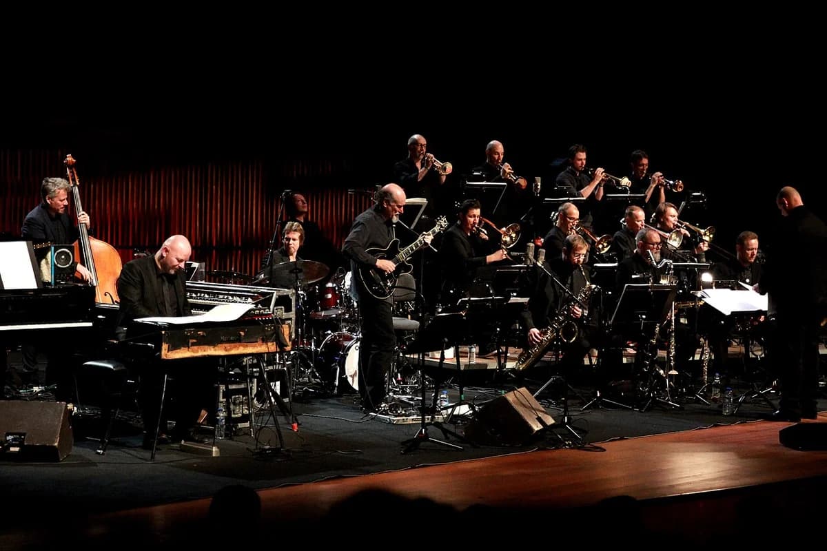 A big band jazz performance on stage with a guitarist soloist and conductor.