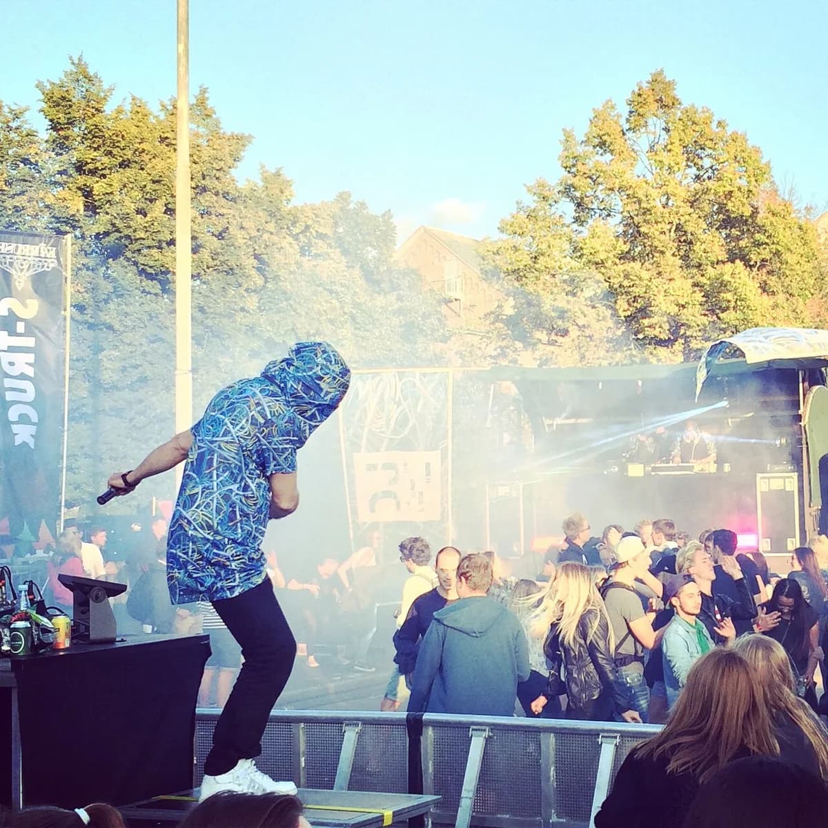 Performer on stage with crowd at outdoor music festival