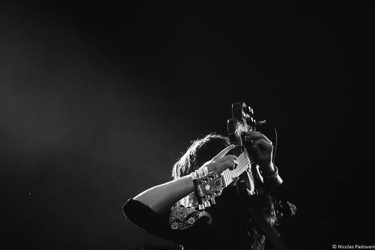 Black-and-white concert photo of a guitarist performing on stage.