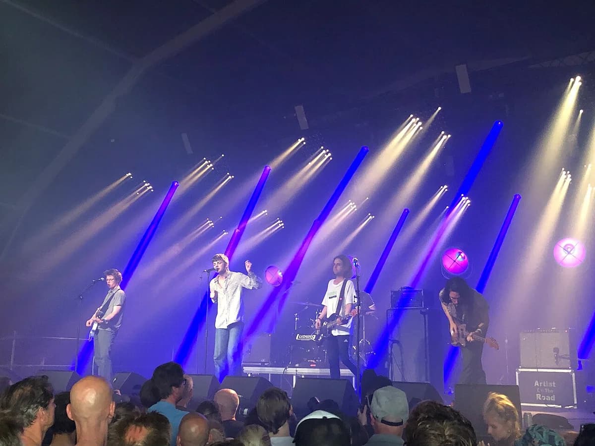 Band performing on stage with blue and white lights at music festival
