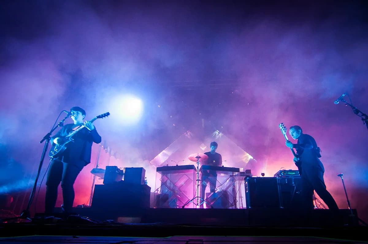 Band performing on stage with vibrant lighting and fog