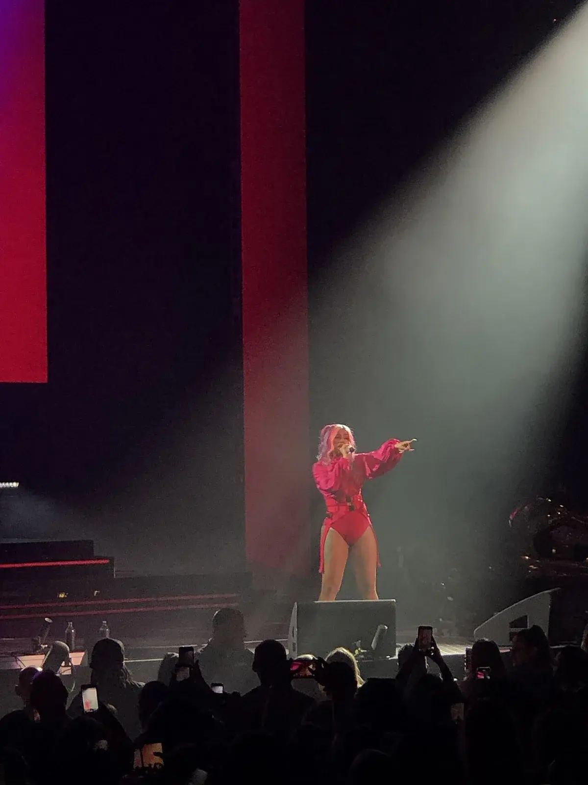 Cardi B performing on stage in a pink outfit under bright lights.