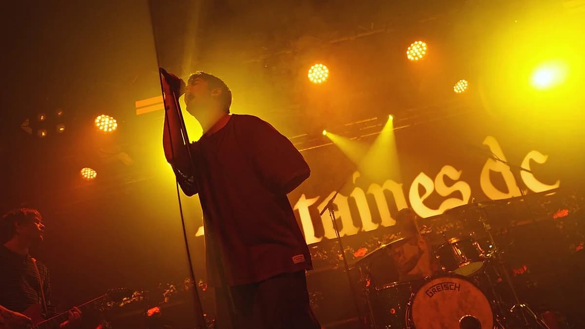 Fontaines D.C. performing live on stage under yellow lights.