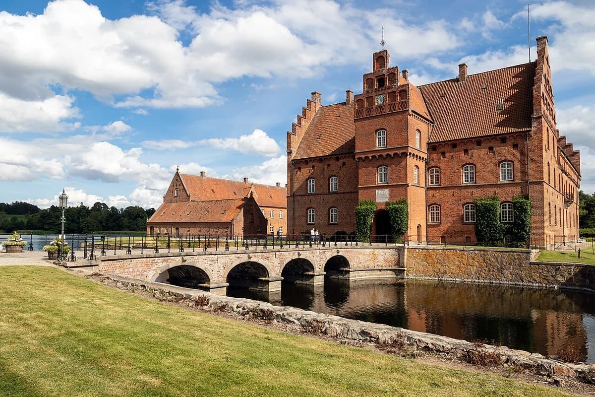 A red-brick castle complex with a bridge over water in Denmark.