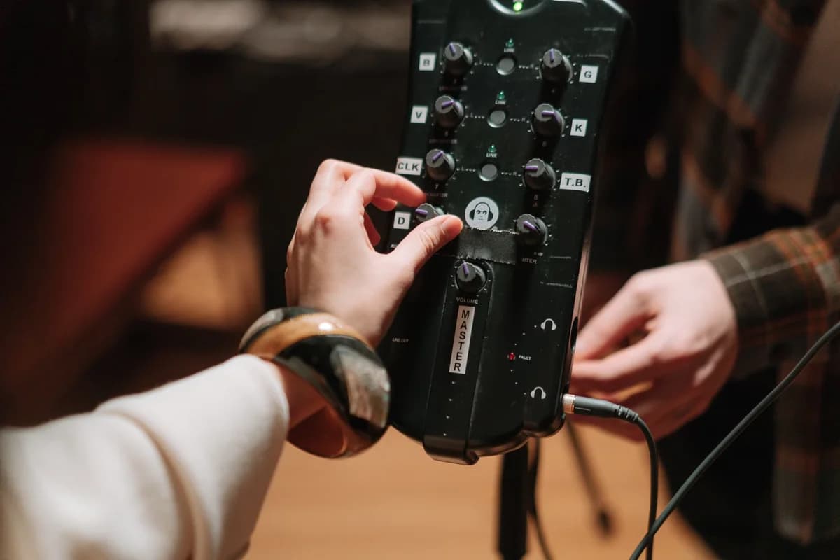 Close-up of hands adjusting controls on audio production equipment