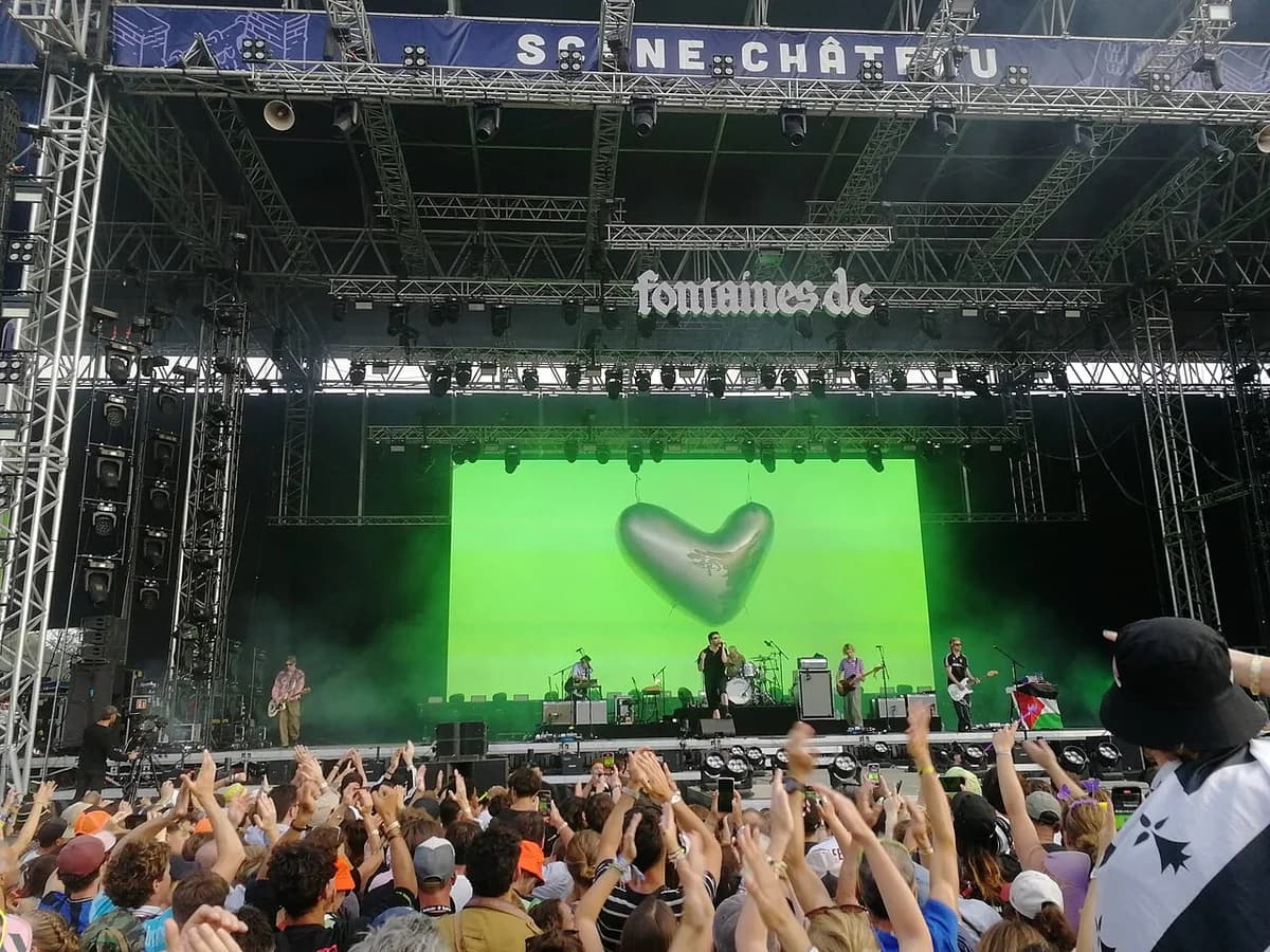Fontaines D.C. performing live on stage at a music festival with a large cheering crowd