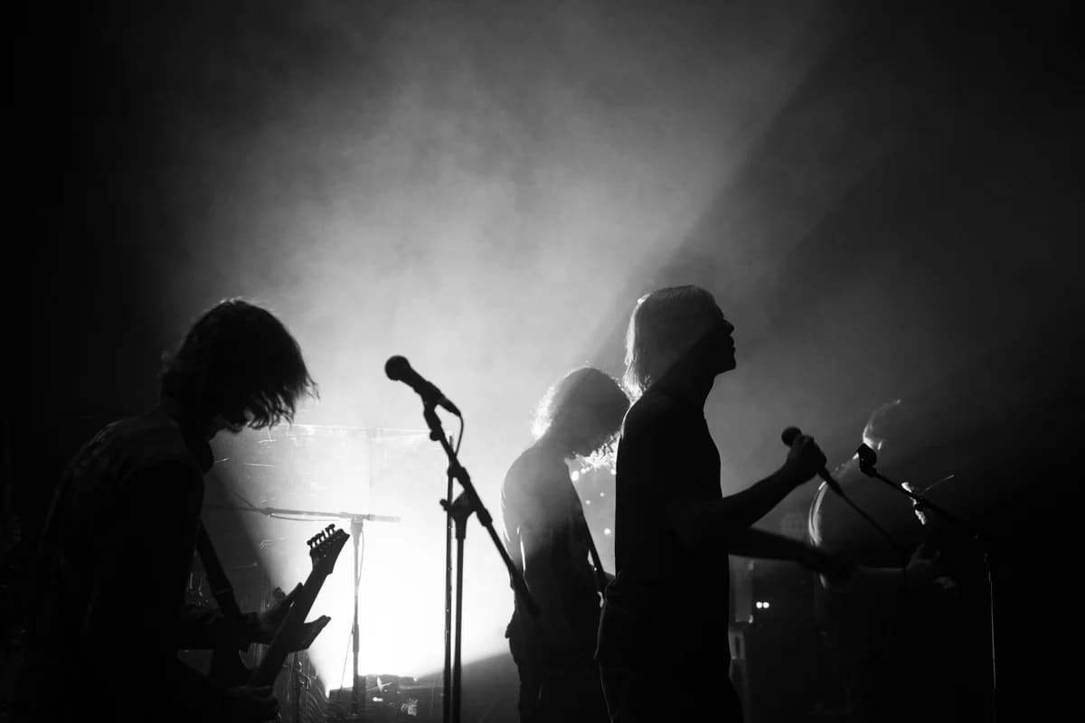Dynamic silhouette of a rock band performing live in dramatic lighting.