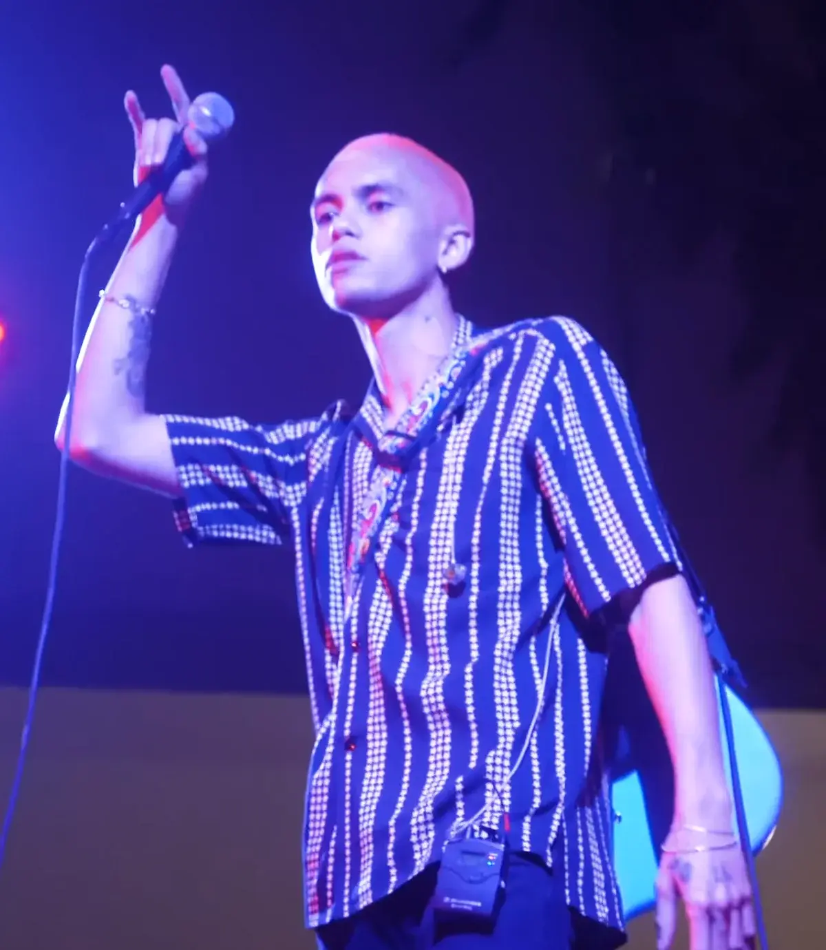 Dominic Fike performing on stage with a microphone.