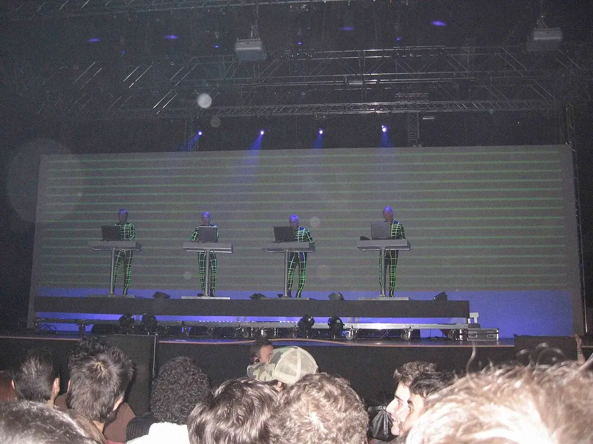 Four members of Kraftwerk performing on stage in illuminated suits.