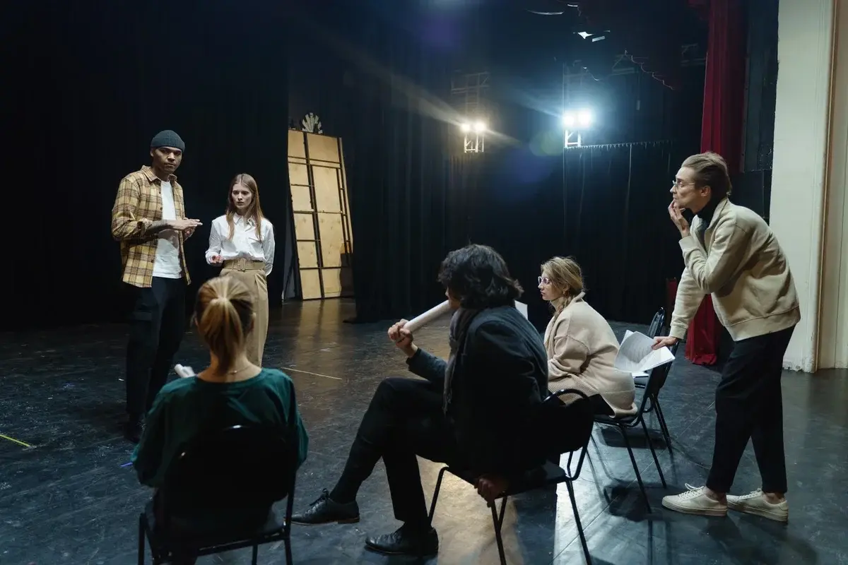 Actors and a director rehearse on a theater stage during a run-through.
