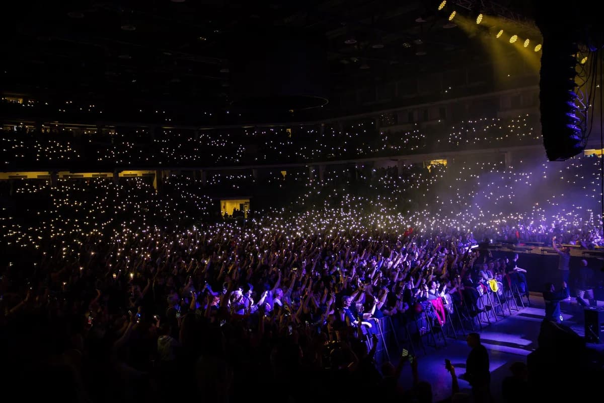 A packed indoor concert with audience lights creating a stunning visual display.