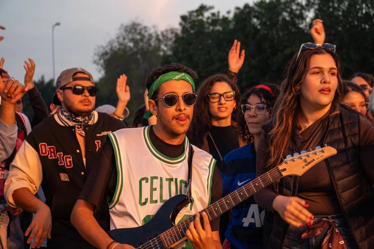 Young adults at an outdoor music festival with a guitarist in the foreground