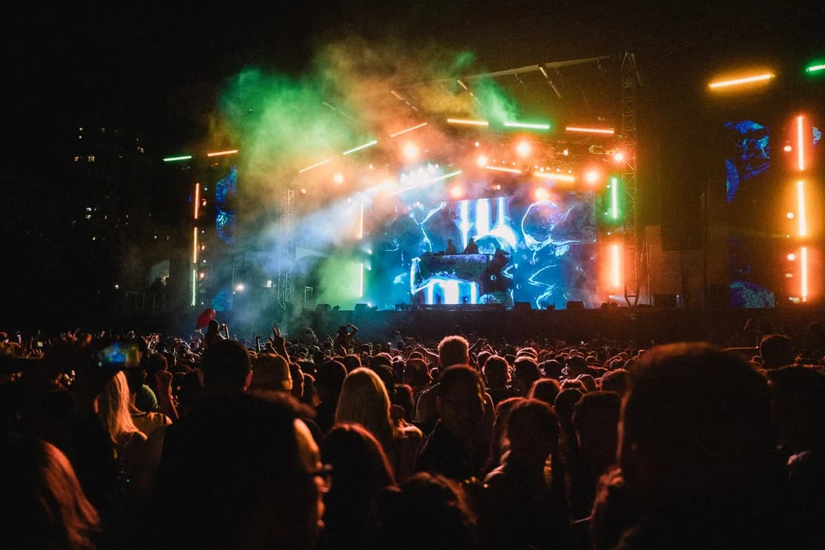 Crowd watching a colorful night concert with bright stage lights