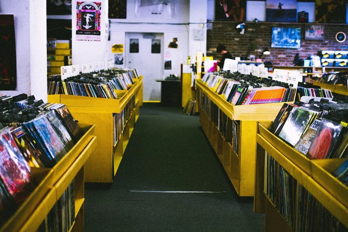 Inside a record store with rows of vinyl records and albums in yellow bins.