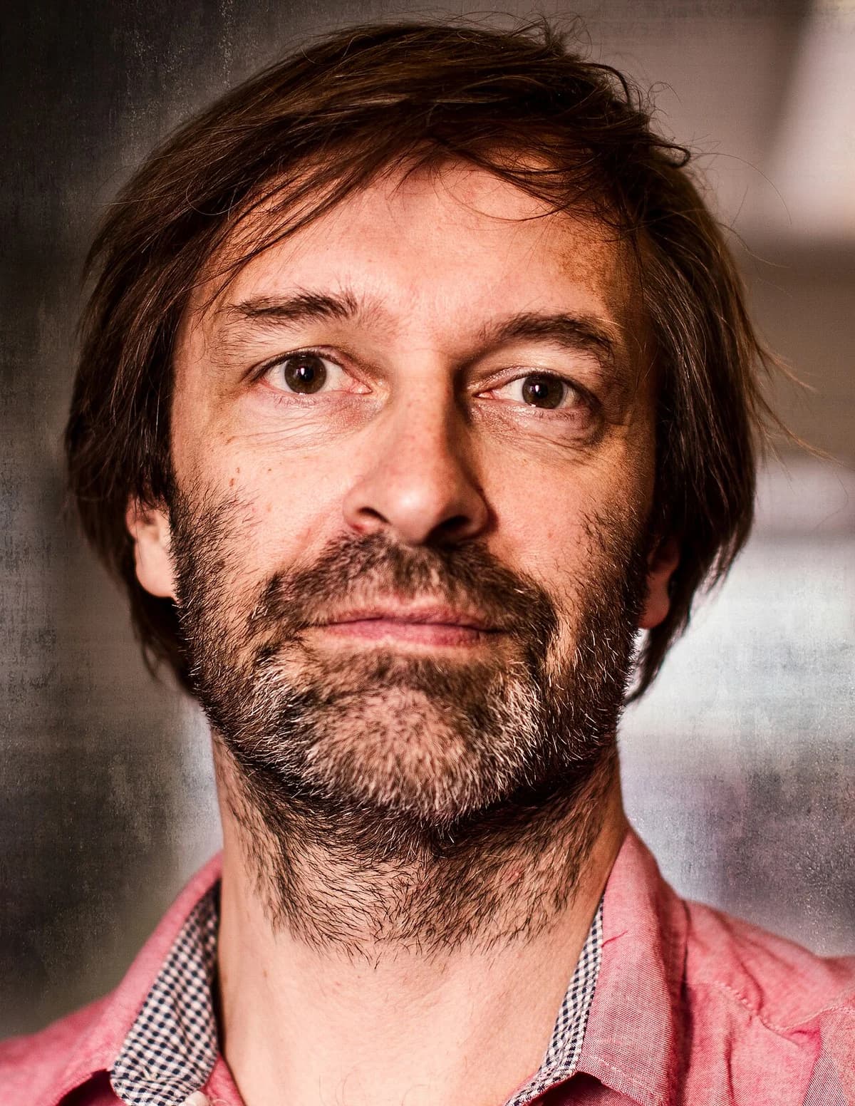 Close-up photo of a bearded man in a pink shirt