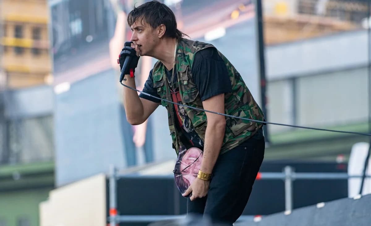 A member of The Strokes sings into a microphone during a live performance on stage.