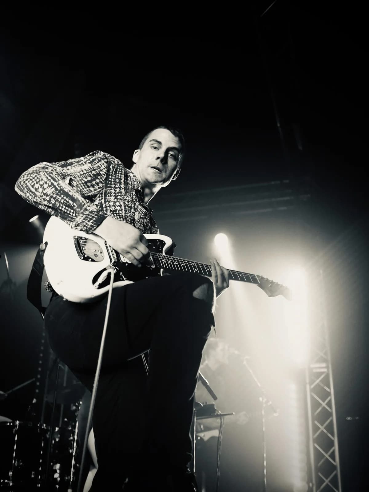 A musician playing electric guitar on stage under bright lights.