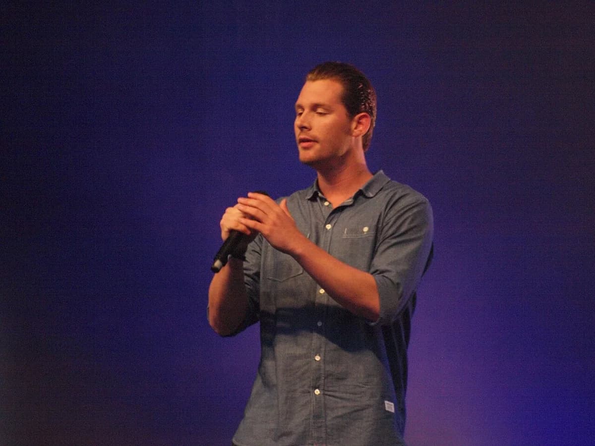 Danish singer Rasmus Seebach holding a microphone on stage.