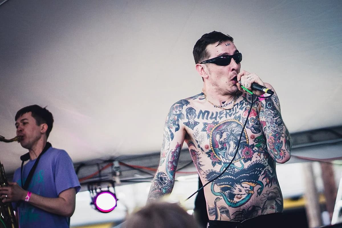 Tattooed male singer performing live with saxophonist