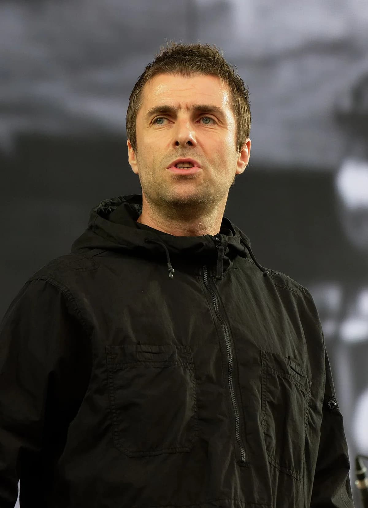 Liam Gallagher performing on stage at a music festival.
