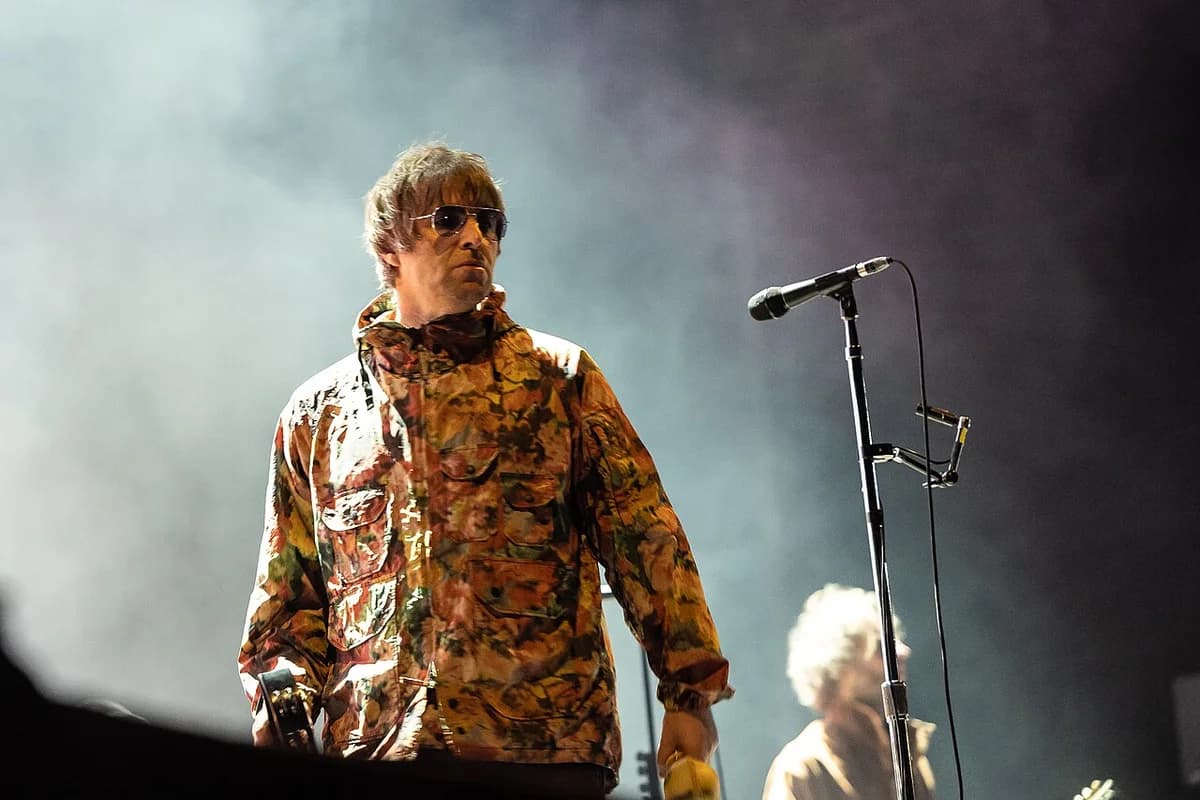 Liam Gallagher standing on stage near a microphone stand.