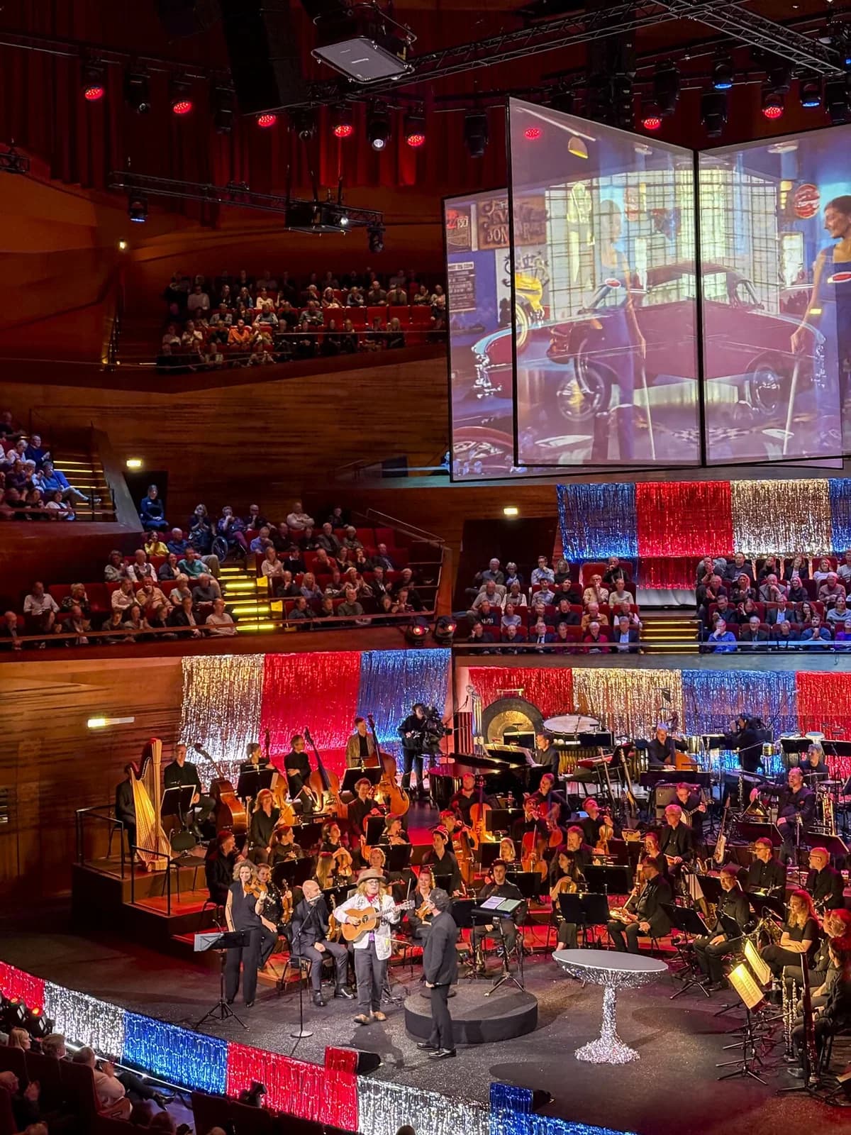 Adeem the Artist performing live on stage with an orchestra in Copenhagen.