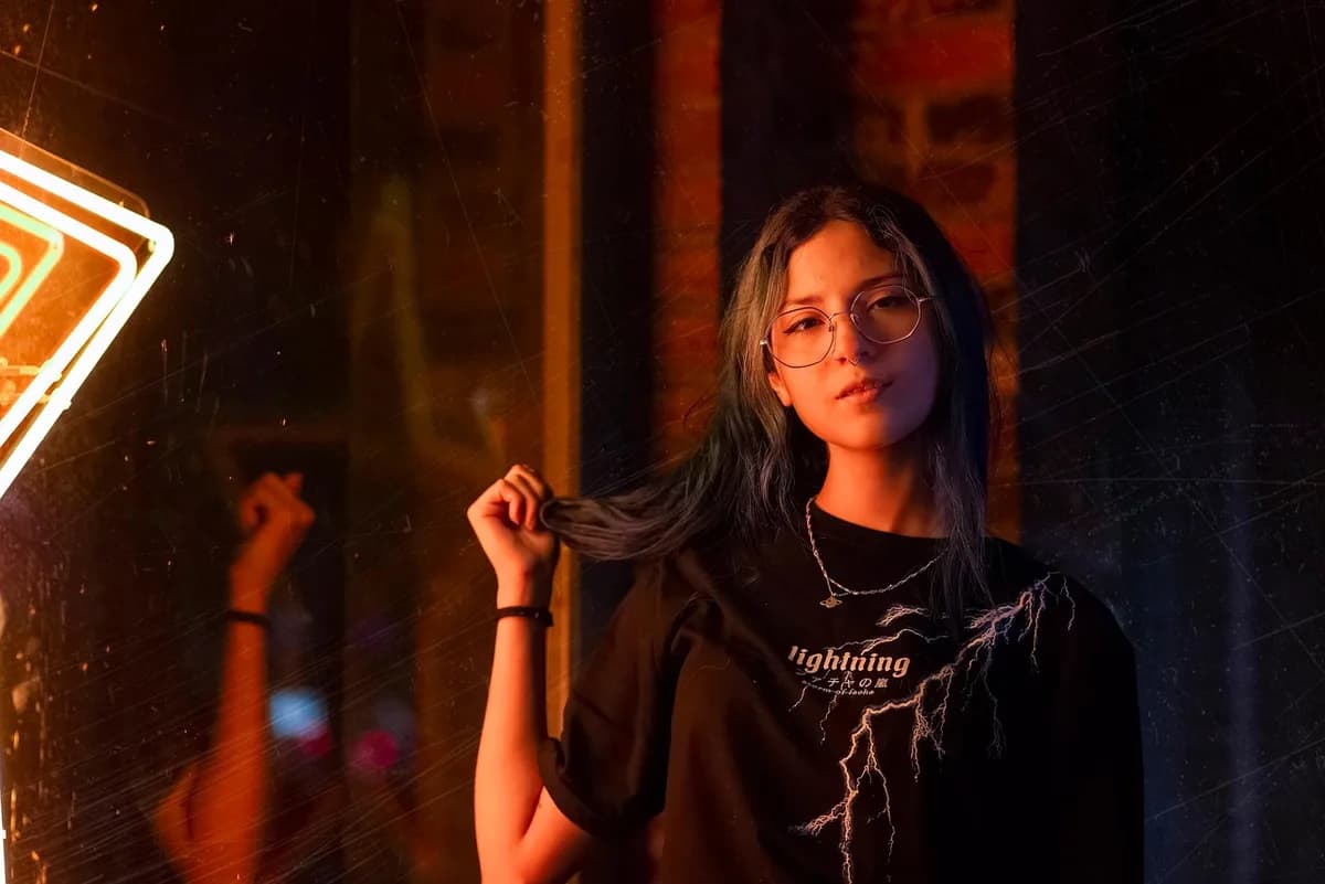 Young woman with glasses posing in neon lighting.