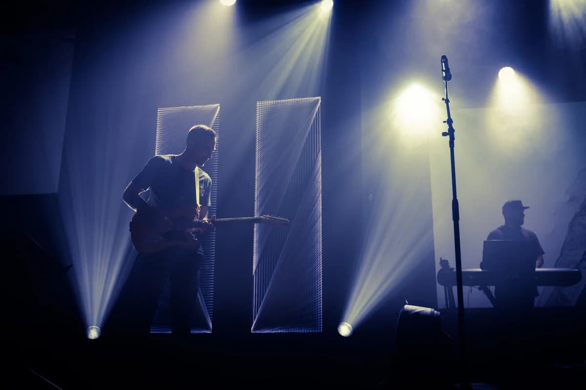 Musician playing guitar on stage with spotlights
