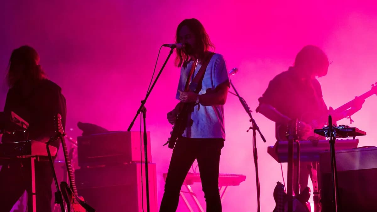 Tame Impala performing on a pink-lit stage.
