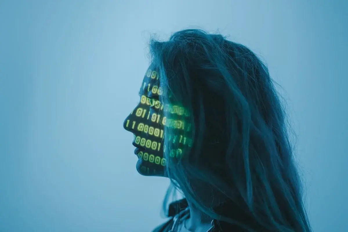 Side profile of a woman with binary code projected on her face.