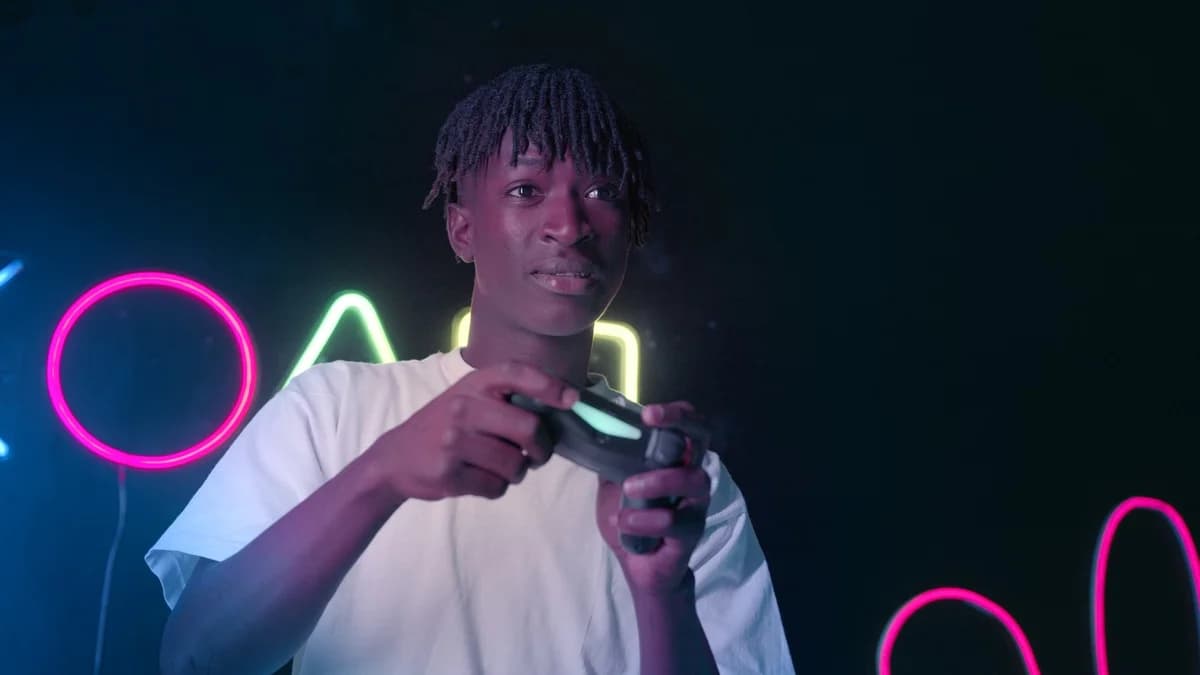 A young man playing video games in neon lighting.