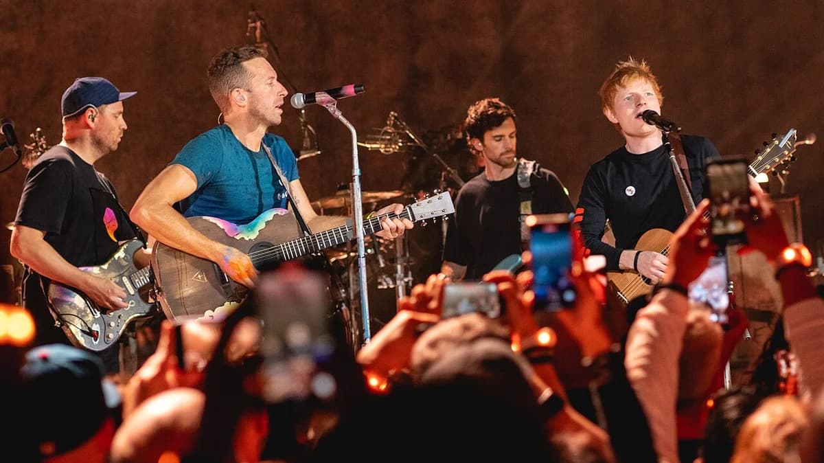 Coldplay and Ed Sheeran performing together onstage at a concert.