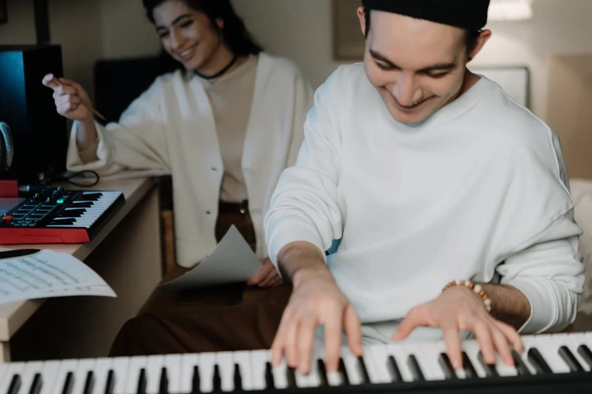 Two young musicians collaborating in a music studio with keyboards and equipment