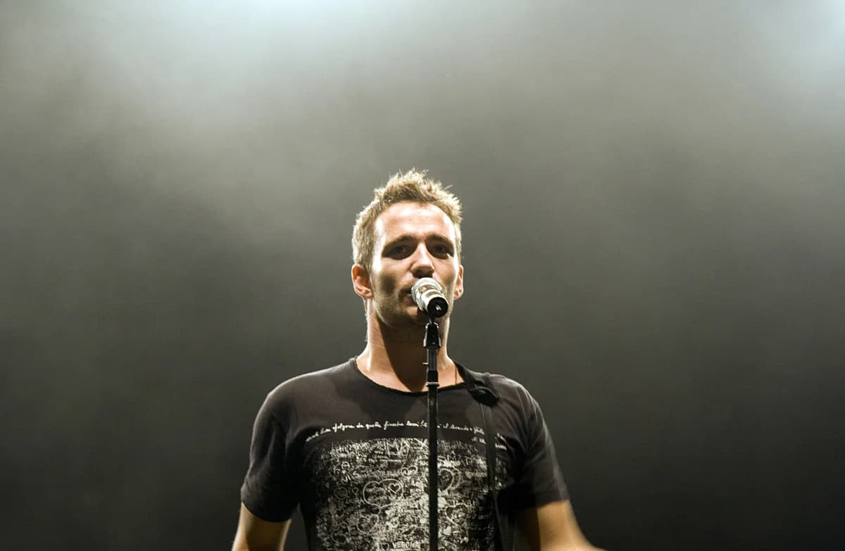 A male singer performing on stage at a microphone.