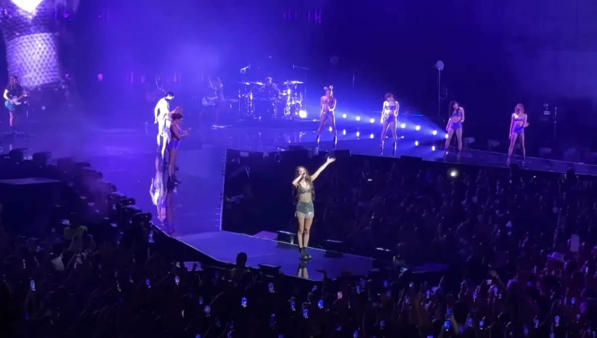 Female singer performing on stage with dancers during a concert