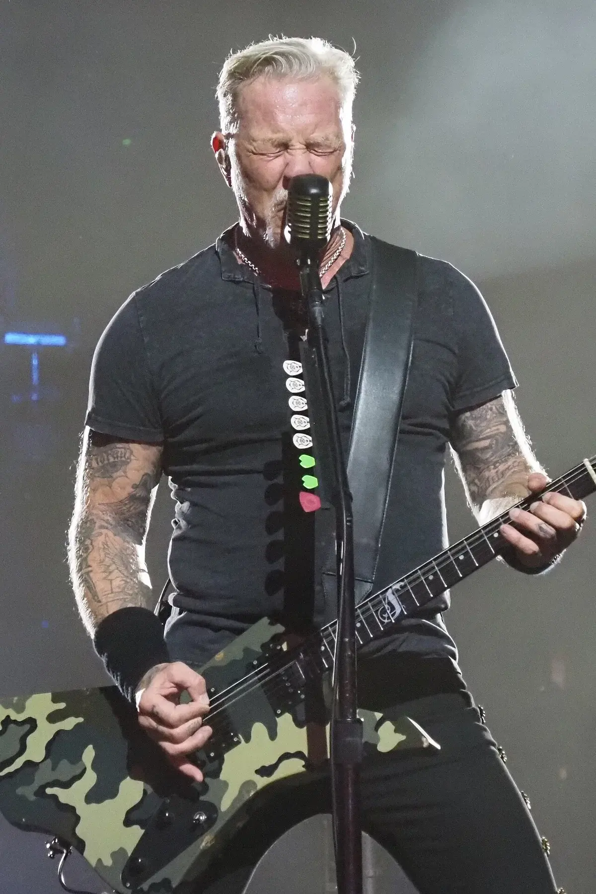 James Hetfield singing and playing guitar on stage during a Metallica concert.