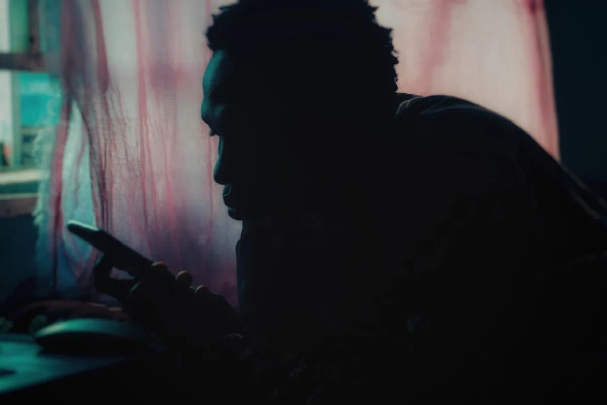 Silhouette of a person using a smartphone by a window.