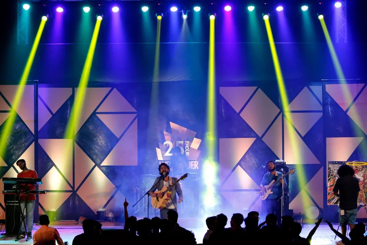 Band performing on stage with colorful lights and audience silhouettes