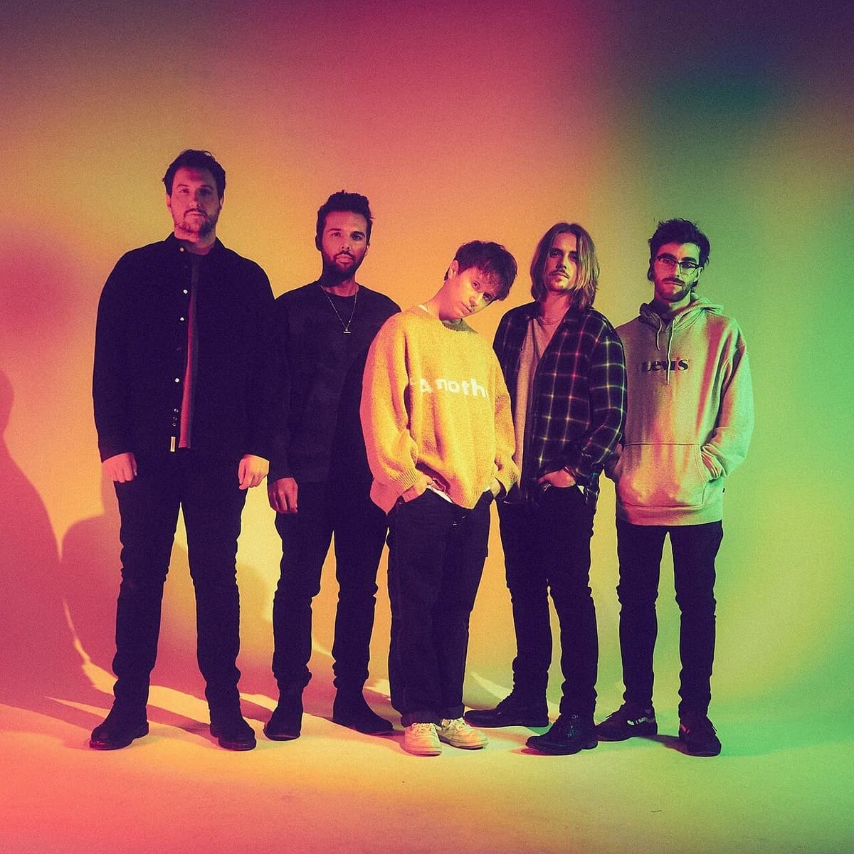 The band Nothing But Thieves posing together in a colorful studio portrait.