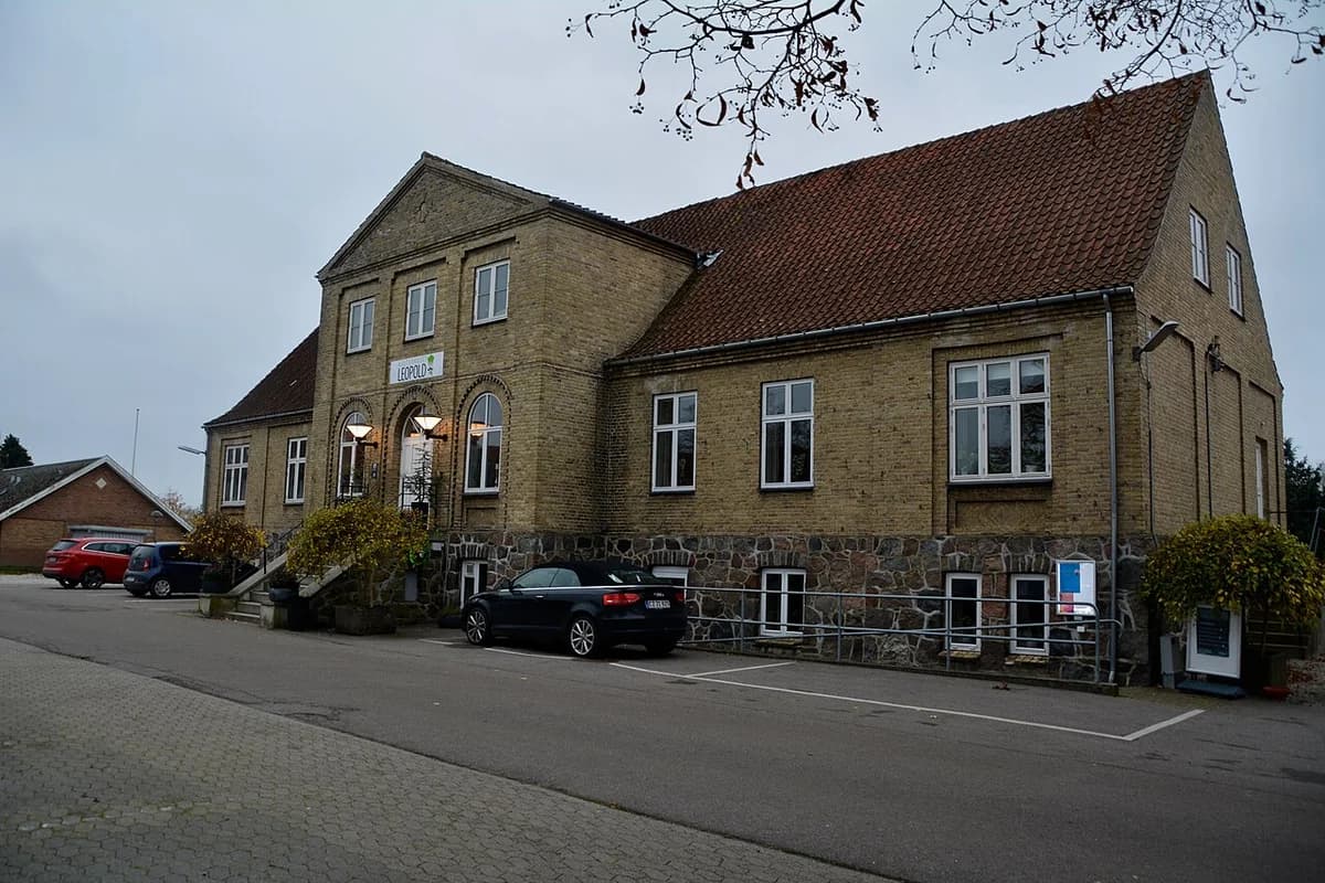 A brick cultural house building with parked cars outside.
