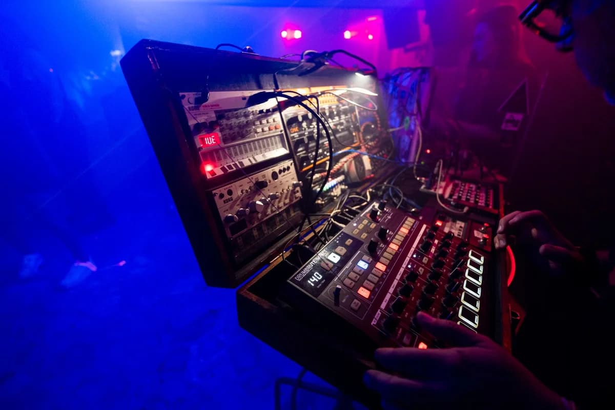 DJ operating an electronic mixer in colorful club lighting