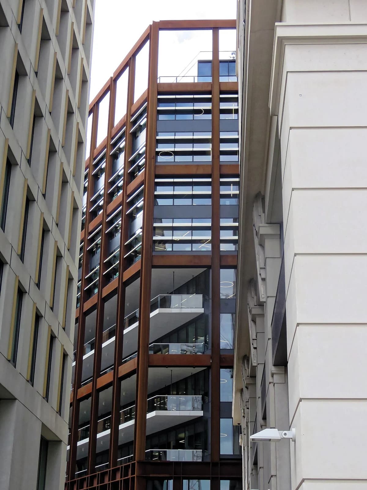 Modern office building viewed between two adjacent buildings in London.